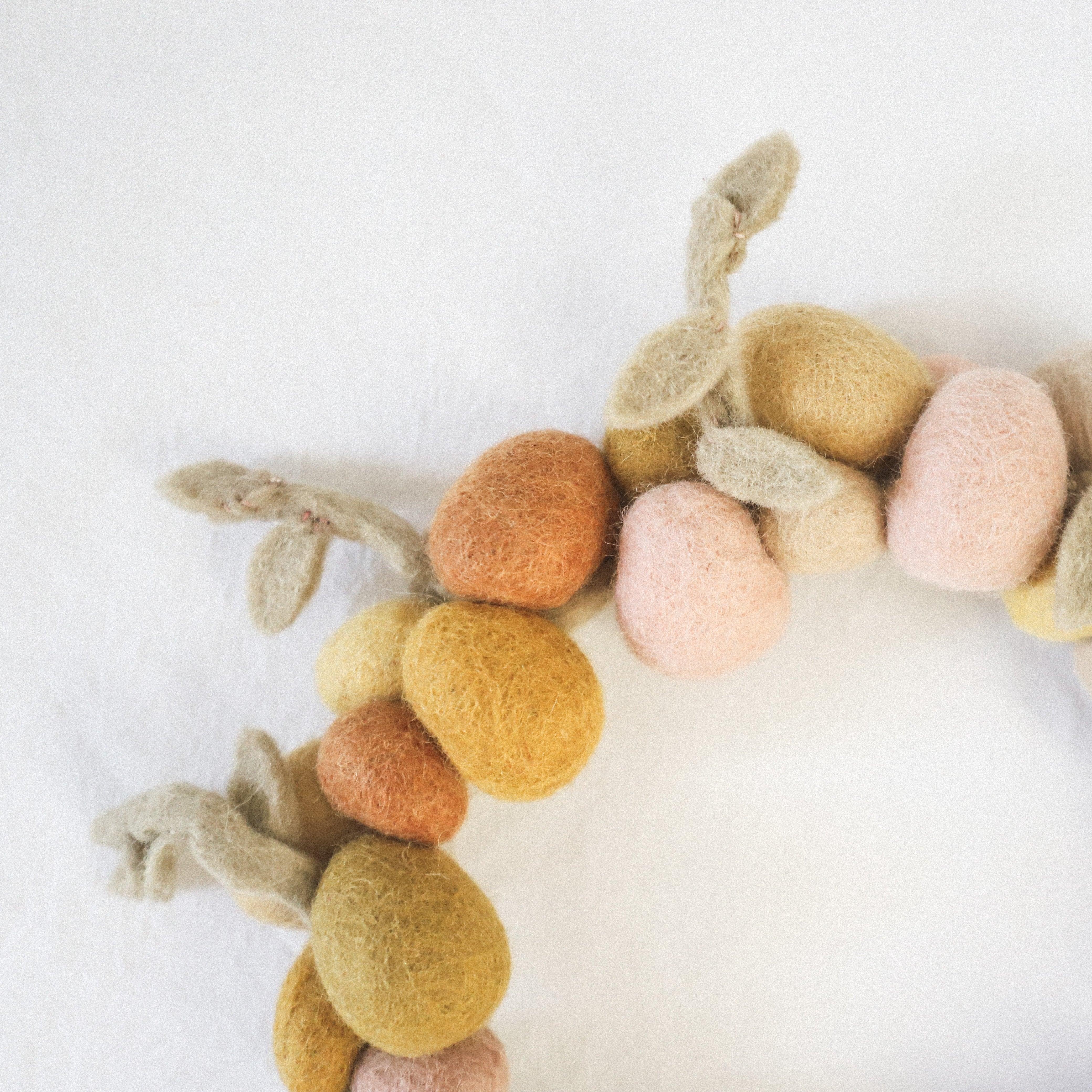 A close-up of the Scandi - Easter Egg Felted Wreath by Grace and Company Ltd, with pastel felt balls and leaves.