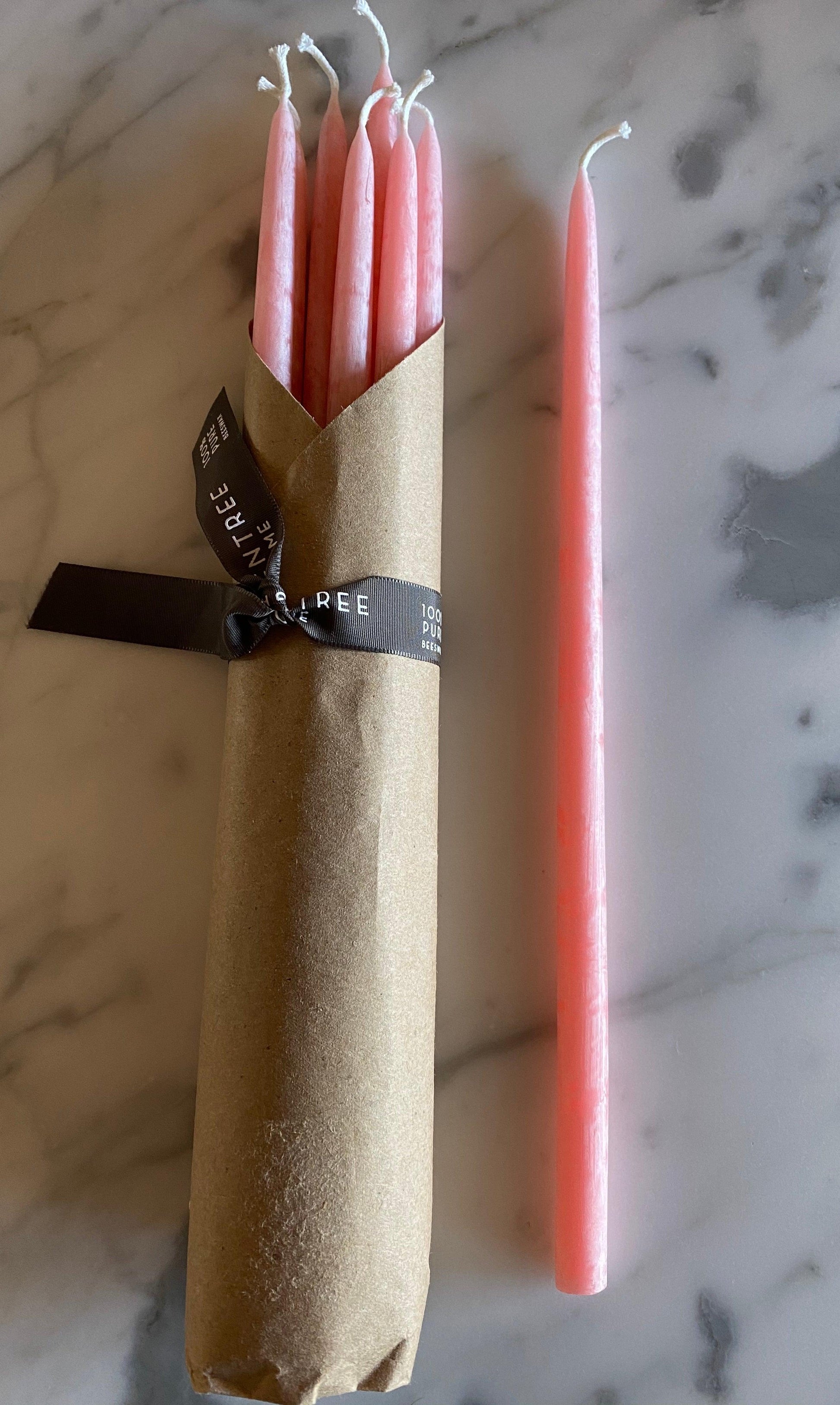Six Green Tree 100% Beeswax Event Candles by Grace & Company ltd, five wrapped in paper with ribbon, one unwrapped on marble.