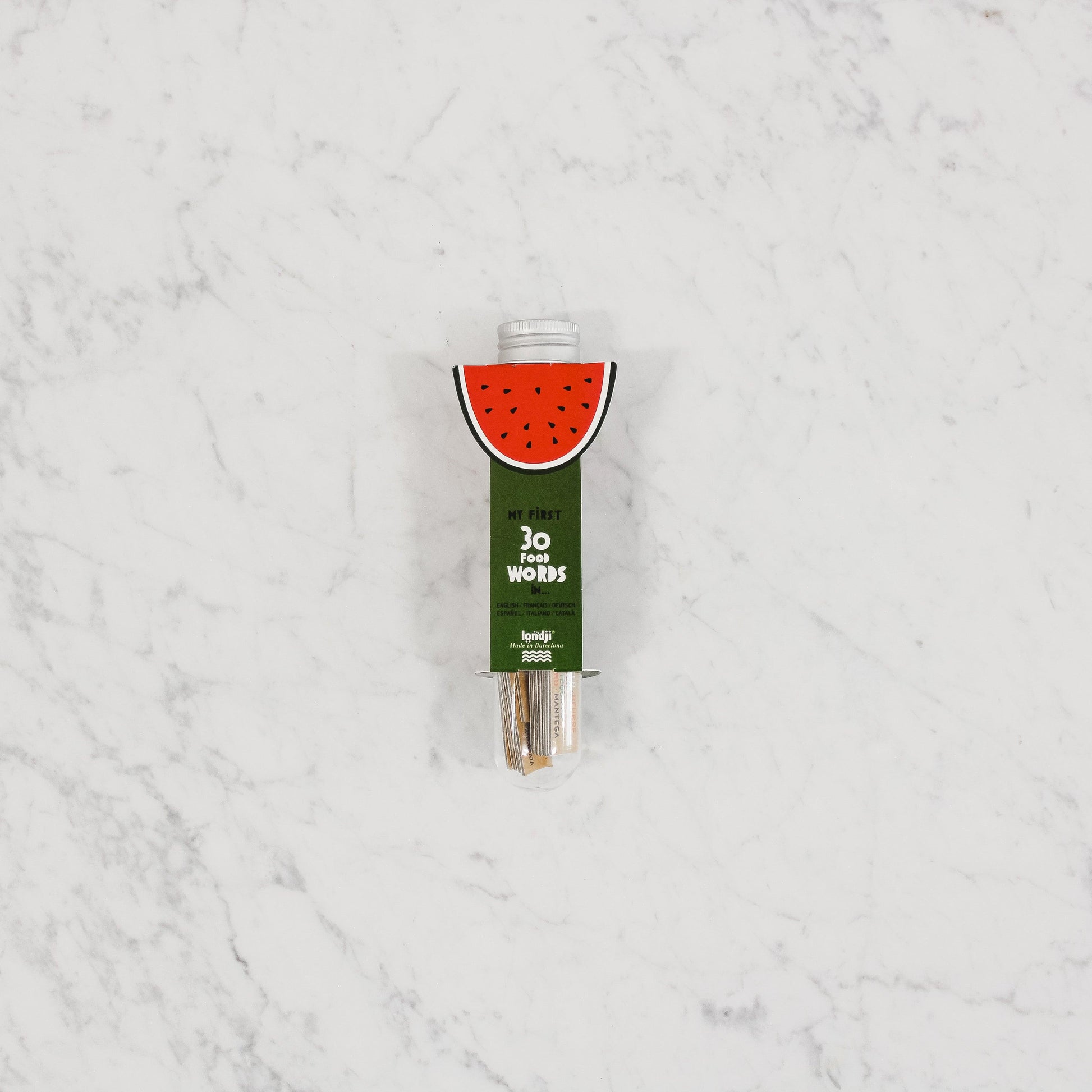 A green tube labeled Londji - Micro Dictionary - Food by Grace & Company ltd on a white marble surface.