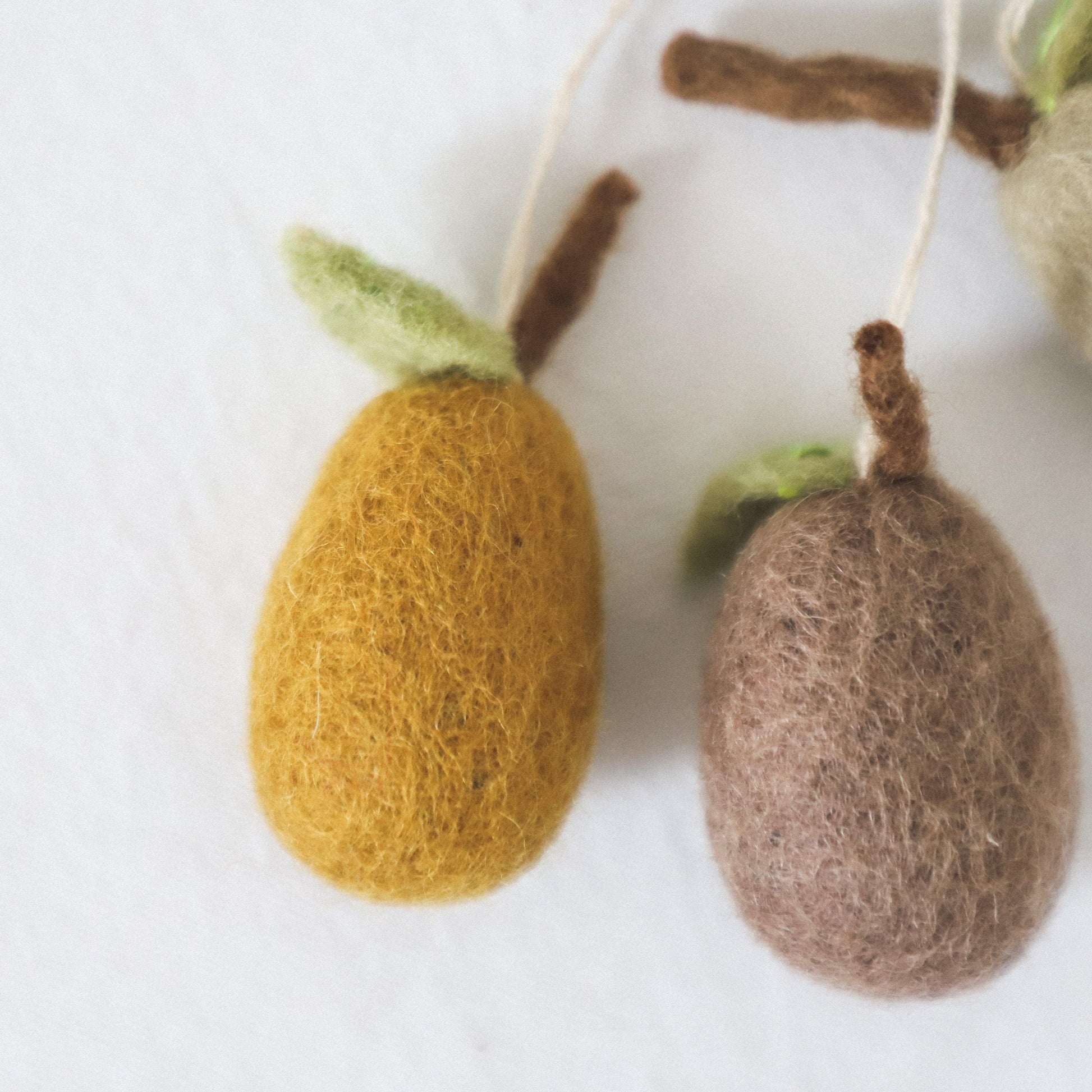 Scandi Felted Pears Ornaments by Grace and Company Ltd: two wool pears, yellow and brown, hang by strings.