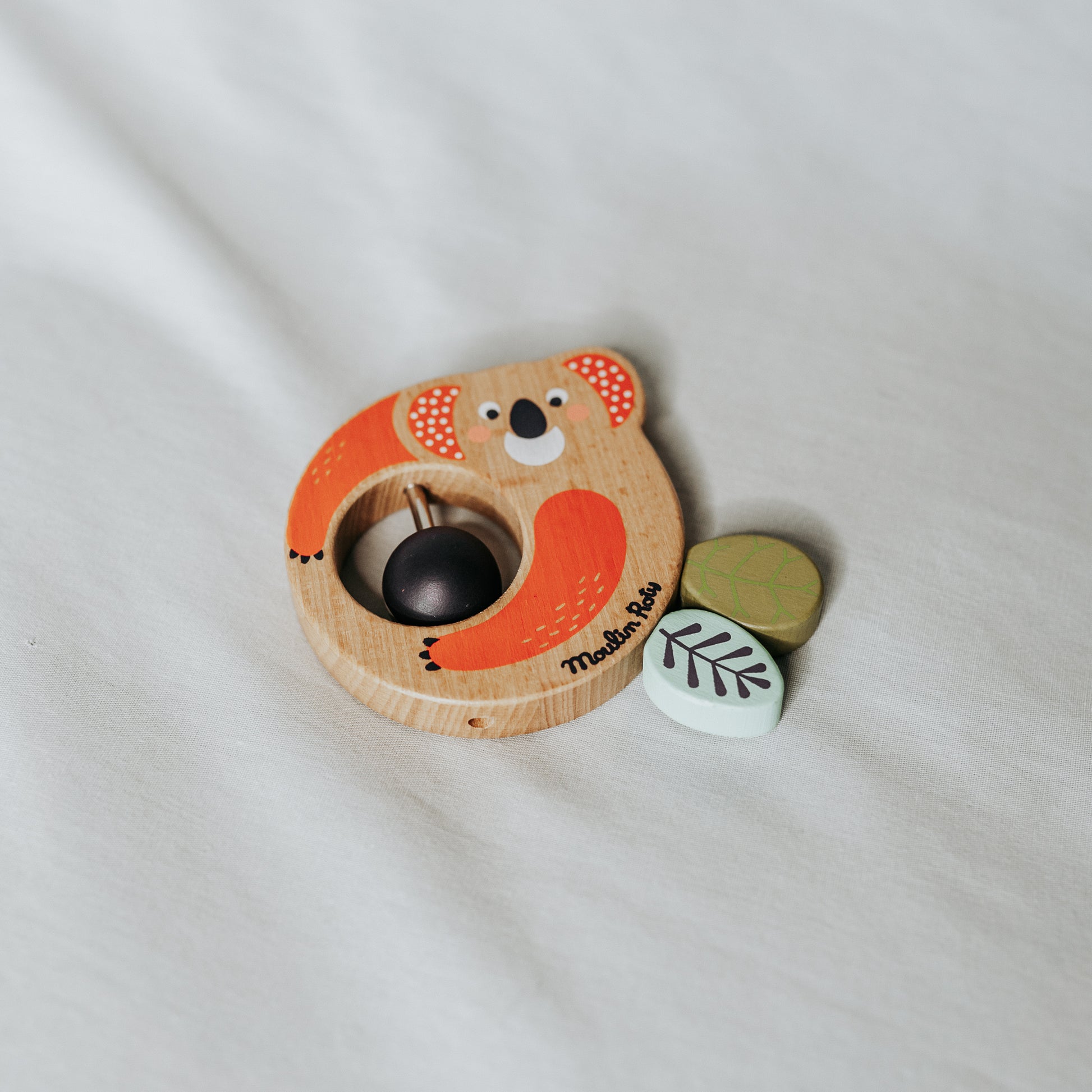 Moulin Roty - Dans la Jungle Wooden Rattle by Grace and Company Ltd, shaped like an orange koala with leaf pieces.
