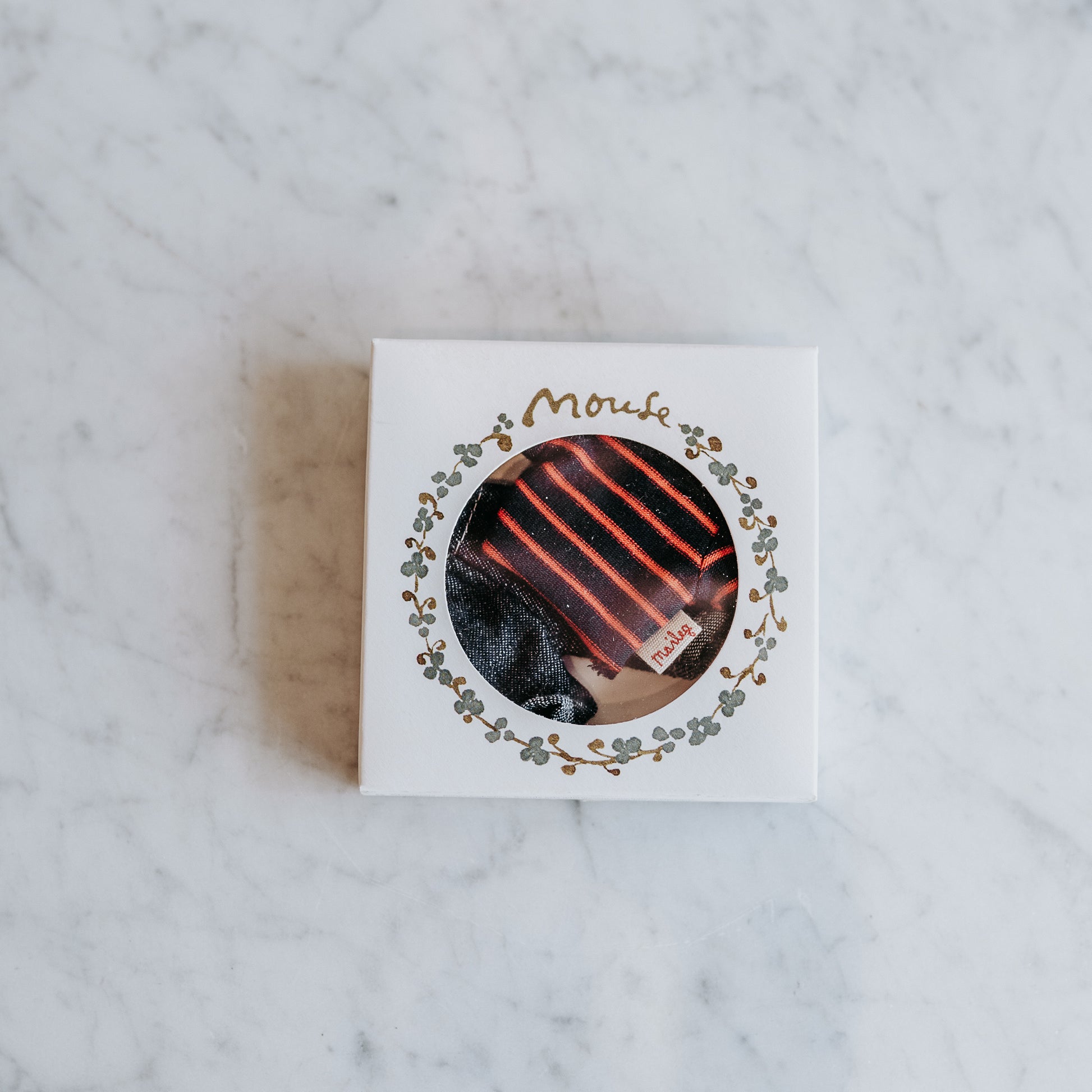 A box with a circular window displays Maileg - Clothing for Mice by Grace & Company on a marble surface.